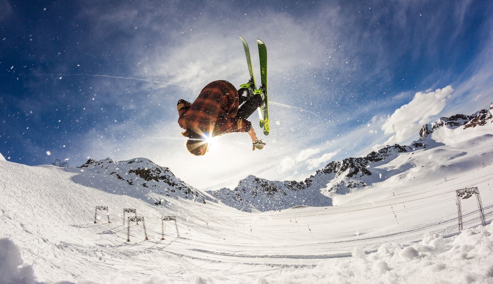 person flip skiing above snow during daytime